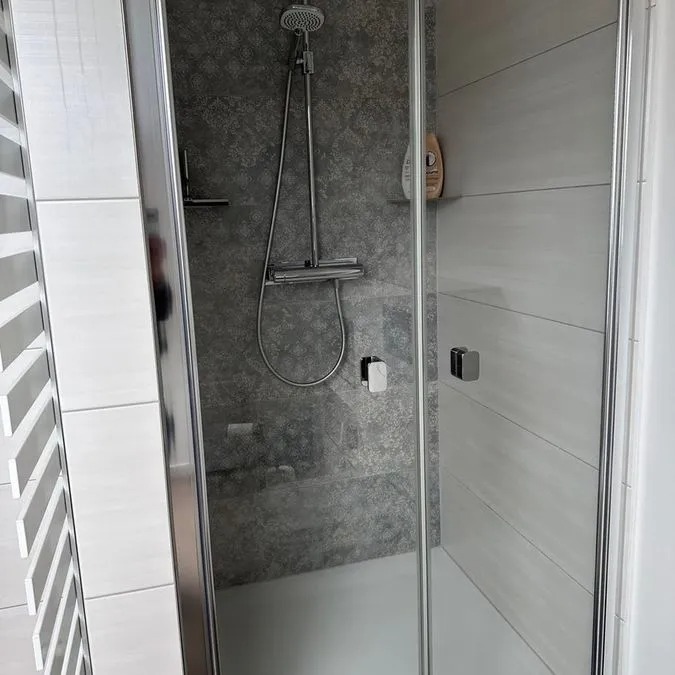 Moderne Dusche mit grauem Stein und Glaswand in neutralen Farbtönen, klar strukturiert