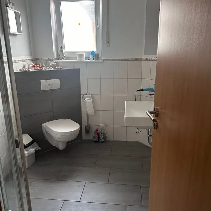 Modern Badezimmer mit Wandtoilette, kleinem Waschbecken und grauen Fliesen