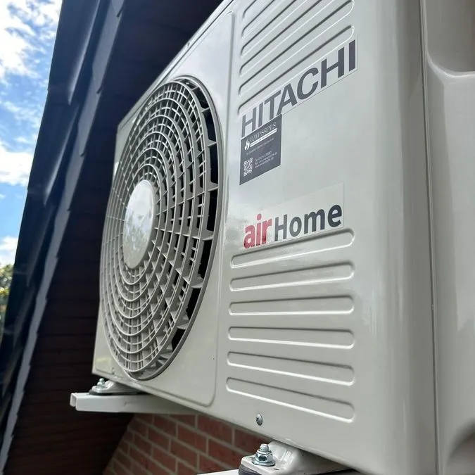 Ein weißes Klimagerät von Hitachi mit der Aufschrift airHome an einer Hauswand