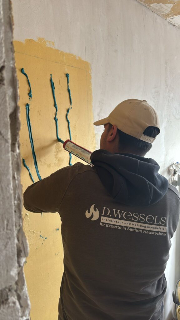 Ein Mann mit beiger Kappe trägt blaue Streifen auf eine gelbe Wand auf